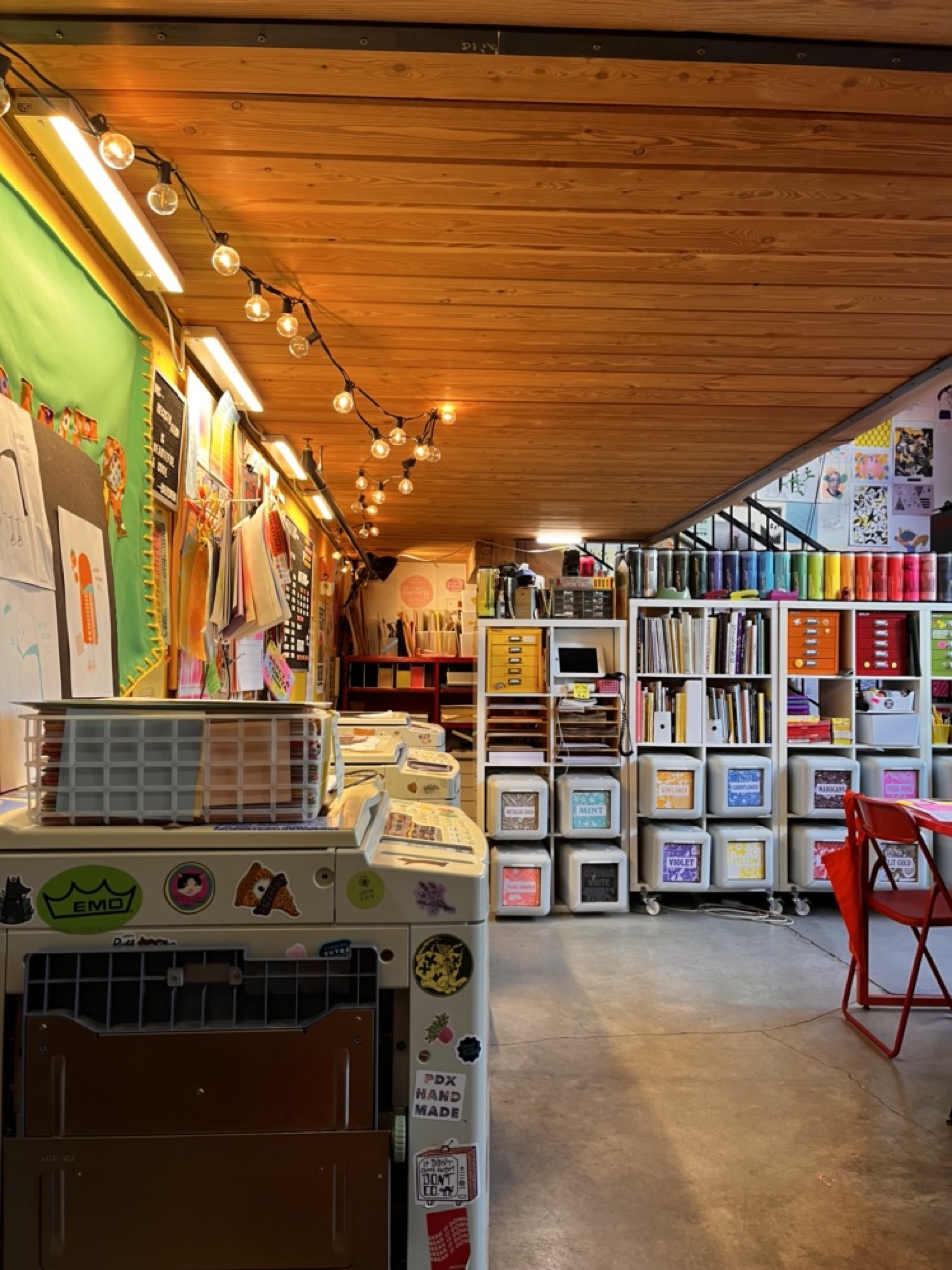 interior of Outlet, underneath lofted area, featuring the wall of riso printers